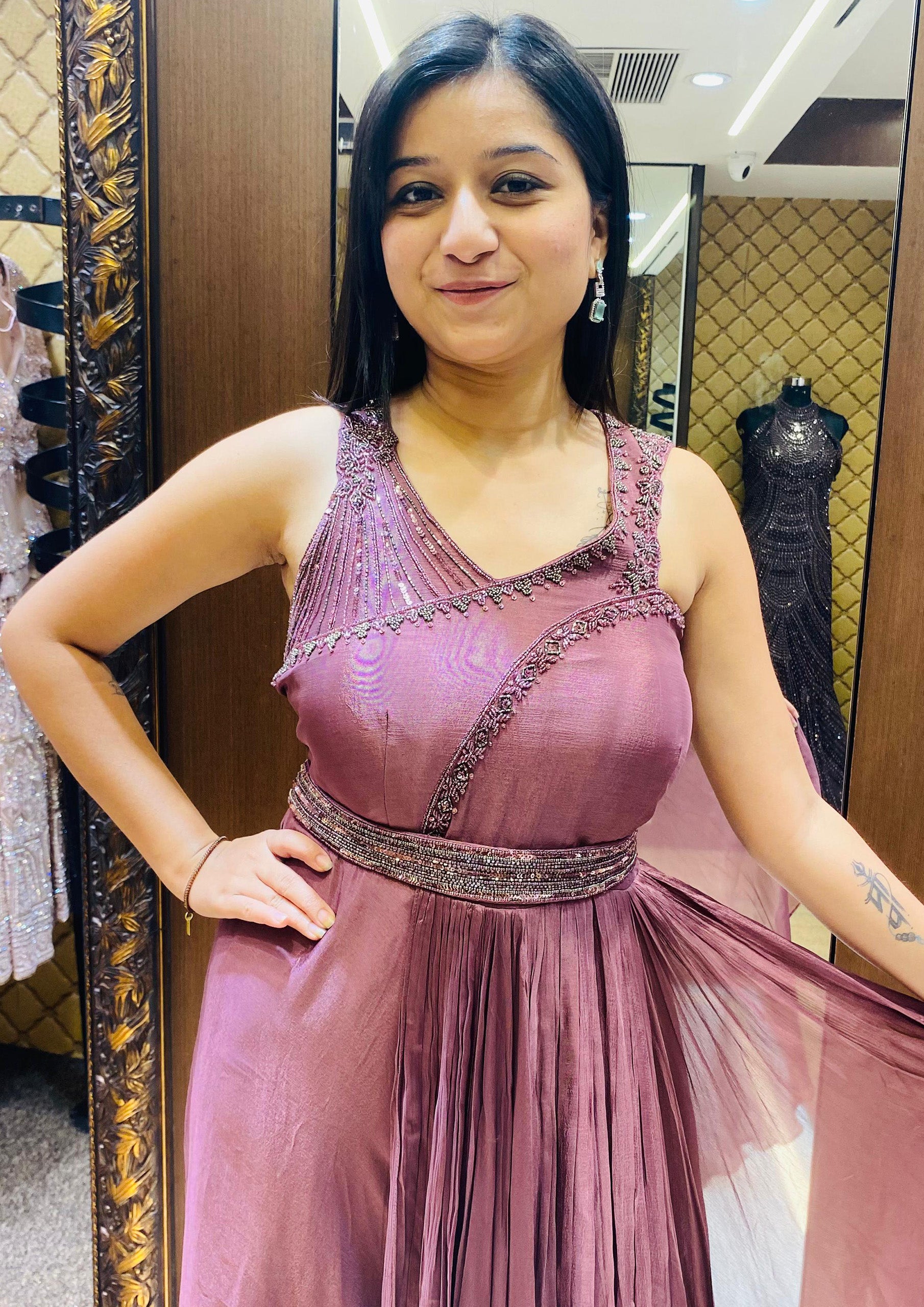 A woman elegantly poses for the camera, wearing a stunning purple gown that enhances her graceful demeanor